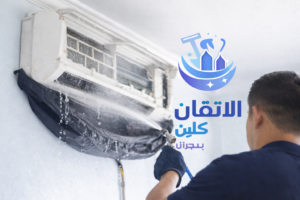 شركة غسيل مكيفات بنجران – فني يقوم بتنظيف مكيف سبليت باستخدام معدات حديثة مع وضع غطاء حماية وظهور شعار الاتقان كلين